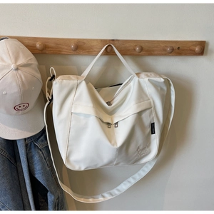 Detail of white nylon tote bag featuring puppy embroidery and brand label on a hook