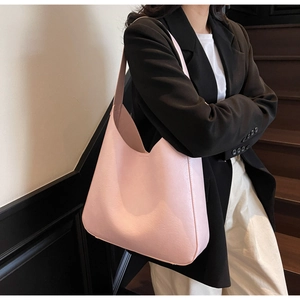 Gros plan sur un sac hobo croissant en cuir rose clair porté par un mannequin
