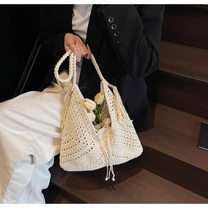 Detail of crochet straw beach bag featuring diamond hollow patterns and decorative tassels