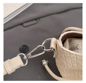 Vue macro du crochet en métal argenté et de la sangle tressée du sac seau blanc cassé