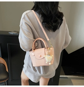 Rosa Handtasche mit Webstruktur und beigem Plüsch-Anhänger in der Seitenrückansicht