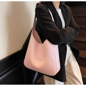 Sac fourre-tout minimaliste en similicuir rose porté à l'épaule par un mannequin