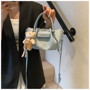 Mini sac seau bleu clair en simili crocodile avec breloque ours mignon sur marches