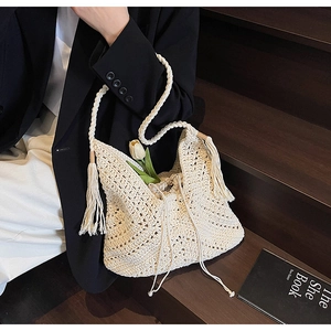Detail of crochet beach bag featuring hollow weave patterns, tassels and drawstring liner