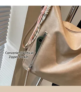 Détail de la poche zippée verticale avec sangle tressée sur un sac en cuir souple beige