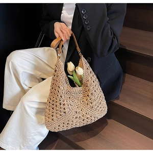 Dettaglio della borsa in paglia intrecciata con manici in pelle marrone e trama chic