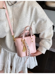 Pink bucket bag with gold hardware and silk scarf shown on model in a soft style