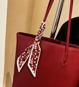 Detail of burgundy leather tote bag handle decorated with a red heart-patterned twilly scarf