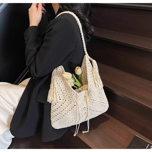 Detail of cream handmade crochet shoulder bag with hollow weaving and long fringe tassels