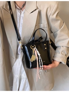 Elegant black patent leather bucket bag with gold hardware and stylish bag charms
