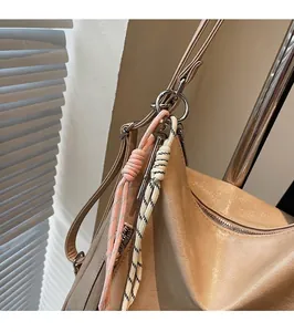 Détail du cabas en cuir mat beige avec pendentif tressé décoratif et anneau métallique argenté