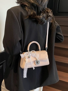 Pink mini crossbody bag with white lace bow and pearl charm shown on model
