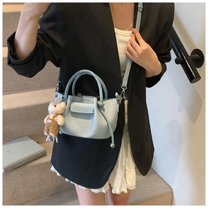 Détail du sac à main bleu clair plissé avec breloque ours et poignées rondes chic