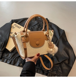 Detail der cremeweißen Handtasche mit Krokodilmuster, braunem Besatz und Anhänger