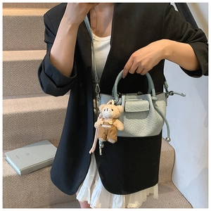 Mini sac seau plissé bleu clair avec breloque ours porté par un mannequin