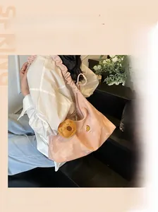 Dettaglio della borsa a spalla rosa a pieghe con ricami e un ciondolo a forma di orso