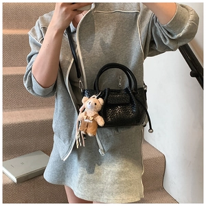 Détail du sac seau tressé noir avec fermeture à cordon et breloque ourson mignon