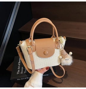 Détail d'un sac à bandoulière blanc tissé avec rabat en cuir marron et pompon peluche