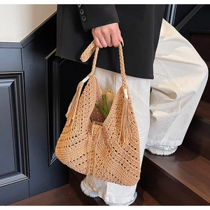Detail of handmade crochet straw tote bag with braided handle and long side tassels