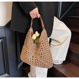 Dettaglio della borsa in paglia intrecciata con manici in pelle marrone e trama crochet
