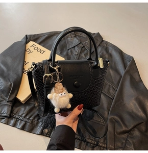 Detail der schwarzen gewebten Lederhandtasche mit Plüschanhänger und festem Griff