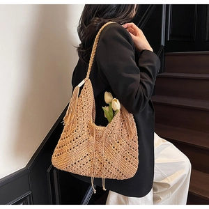 Detail of crochet straw shoulder bag with long tassels and hollow geometric weave pattern
