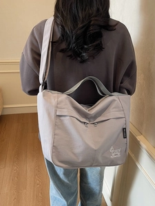Large grey nylon tote bag with puppy print shown on model in cozy home setting
