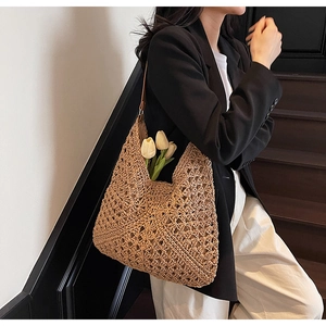 Dettaglio della borsa tote in paglia intrecciata a righe traforate indossata da una modella