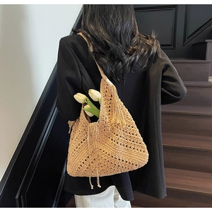 Detailed close-up of a khaki crochet straw bag with hollow knit patterns and long tassels