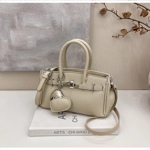 Dettaglio borsa a mano beige in pelle litchi con chiusura argento e ciondolo cuore