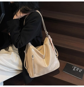 Borsa hobo kaki indossata da una modella con cerniere e ciondolo intrecciato rosa