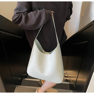 Détail d'un sac Hobo vert clair en similicuir grainé porté par un mannequin chic