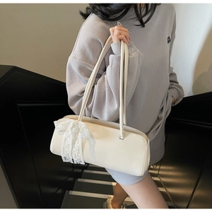 Detail of creamy white rectangular underarm bag featuring a delicate lace bow accent