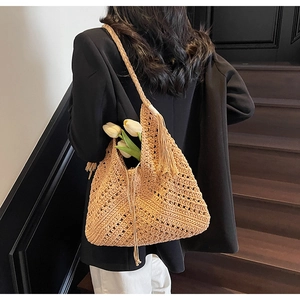 Detail of light brown crochet shoulder bag with hollow texture and decorative tassels