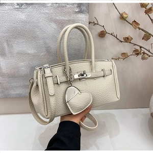 Dettaglio della borsa in pelle beige con trama a grana e chiusura in metallo
