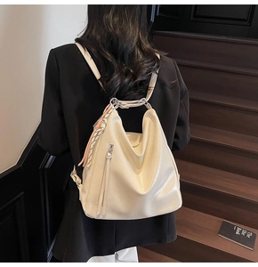Dettaglio dello zaino hobo in ecopelle beige con cerniera a nappa e ciondolo intrecciato