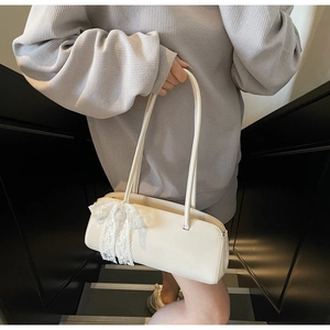 Detail of minimalist beige faux leather shoulder bag with white lace bow charm
