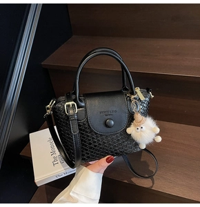 Détail d'un sac à main noir tressé avec breloque en peluche et finitions dorées