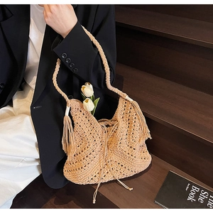 Detail of handmade crochet straw bag with hollow texture and side tassels for summer