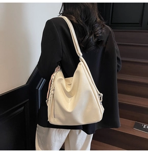 Dettaglio borsa tote in pelle PU crema con cerniera laterale e nappa rosa decorativa