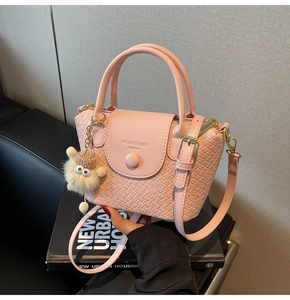 Detailansicht der hellrosa Handtasche mit Webstruktur und süßem Bommel-Anhänger