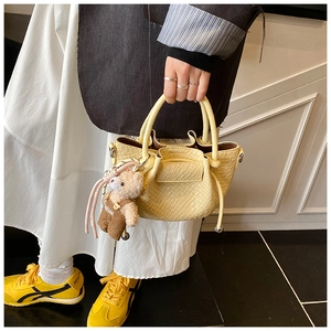 Détail du mini sac seau jaune clair à motif crocodile avec un charmant ours en peluche