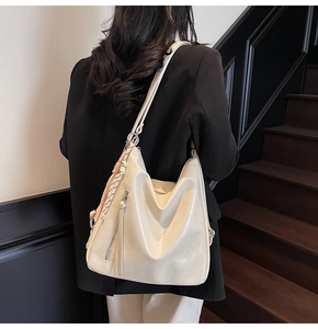 Dettaglio della borsa hobo in ecopelle crema con cerniera laterale e sciarpa di seta