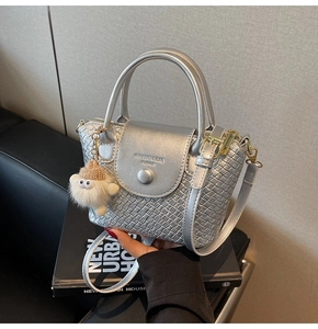Detailansicht der silbernen Handtasche mit Webstruktur, Riemen und Plüsch-Anhänger