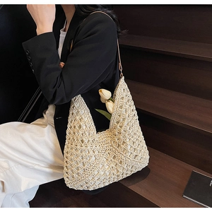 Dettaglio della borsa tote in maglia intrecciata a mano con tracolla in un contesto lifestyle