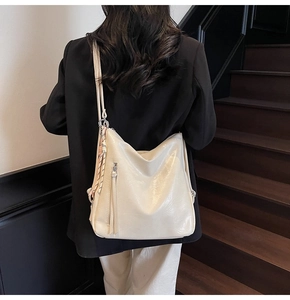 Borsa tote in pelle bianco crema con lunghe nappe mostrata sulla spalla di una modella