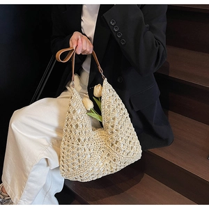 Dettaglio della borsa in paglia intrecciata con tracolla in pelle marrone di alta qualità