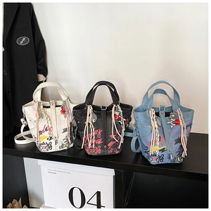 Detail of trendy graffiti bucket bags in white, black, and denim with cute accessories