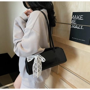 Close-up of black underarm bag featuring a delicate white lace bow on the side detail