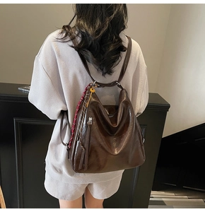 Dettaglio dello zaino in pelle cerata marrone scuro con ciondolo a foulard a quadri